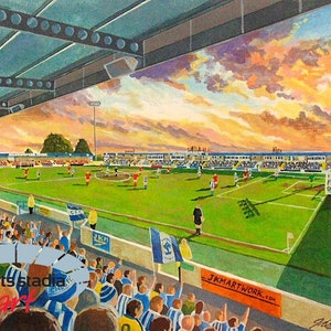 May include: A painting depicting a football match in progress at a stadium. The stands are packed with spectators, and the players are visible on the green pitch. The sky is painted with warm sunset colors.