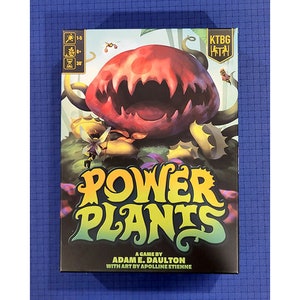 May include: A board game box with a bright yellow and green title "Power Plants". The box features a cartoon illustration of a large, red, toothy plant with green vines and leaves.