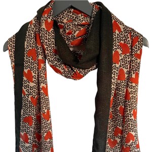 May include: A scarf with a black and white heart pattern and red hearts. The scarf has a black border.