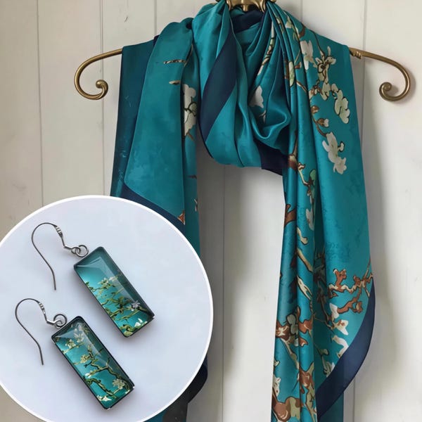 May include: A teal scarf featuring a brown branch and white flower print, paired with a set of rectangular drop earrings that display the same floral pattern. The earrings have silver-toned metal hooks and a smooth, glossy finish on the front surface.