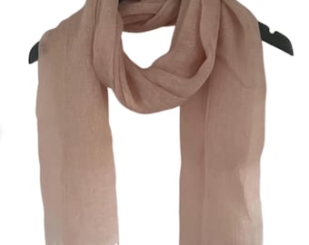 May include: A light pink scarf with a fringed edge, displayed on a black hanger. The scarf is made of a lightweight material and is draped to show its length and texture. The scarf's color is a soft, muted pink.