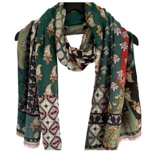 May include: A patterned scarf in shades of green, pink, and brown, with paisley and floral motifs. The scarf is displayed on a black hanger. The scarf's design includes geometric shapes.