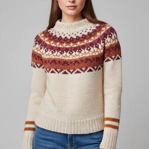 May include: Cream-coloured jumper with a high neckline and long sleeves. The yoke features a geometric pattern in shades of burgundy, brown, and white. The cuffs have two brown stripes. A cosy, warm garment for cooler weather.