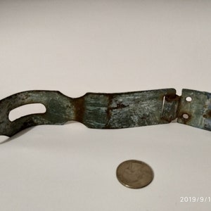 May include: A rusty metal latch with a curved arm and a hinged section. The latch is painted a faded green colour and has two holes in the hinged section.