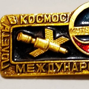 May include: A gold-colored pin with a black and red globe, a telescope, and the text "Комета В Космос Международные Интеркосмос" in Cyrillic.