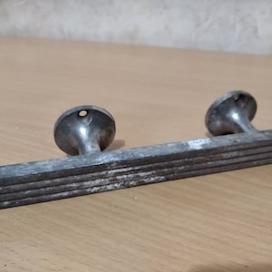 May include: A silver metal door handle with a ribbed design and two round knobs.