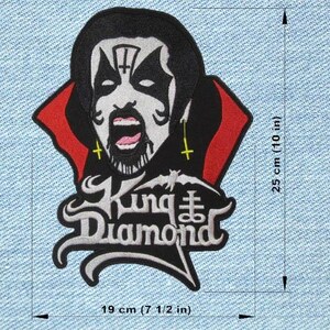 May include: Embroidered patch featuring a stylized portrait of King Diamond in black, white, and red. The patch is approximately 19 cm wide and 25 cm tall, with the band's name displayed in a gothic font.