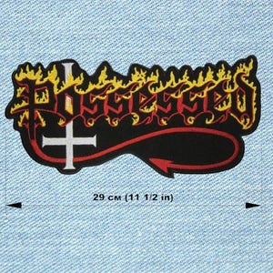 Peut inclure: Écusson noir avec le mot "POSSESSED" en rouge, avec des flammes jaunes. Une croix blanche est à gauche, avec un motif en forme de flèche rouge en dessous. Mesure 29 cm de long.