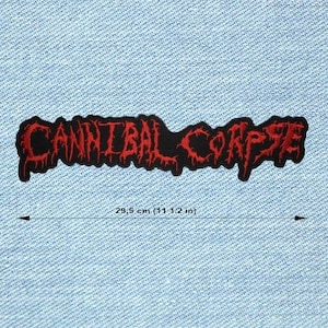 Può includere: Una toppa nera con la scritta rossa "CANNIBAL CORPSE". La toppa è lunga 29,5 cm ed è su uno sfondo di denim blu chiaro. Il testo ha un font stilizzato a goccia.