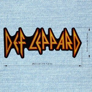 May include: A Def Leppard patch, measuring 11.6 inches long and 4.5 inches high. The patch features the band's logo in yellow and orange on a black background. The patch is rectangular and is set against a light blue denim background.