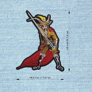 Peut inclure: Écusson brodé représentant une figure à tête de bouc en cape rouge, tenant une épée. Le patch mesure environ 24 cm de haut et 19,5 cm de large. La figure a une tête dorée et un corps brun. Le patch est sur un fond en denim bleu clair.