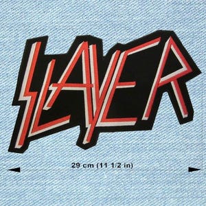Puede incluir: Un parche negro con la palabra "SLAYER" en una fuente estilizada. Las letras están delineadas en blanco y rojo, sobre un fondo negro. El parche mide 29 cm (11 1/2 pulgadas) de largo. El parche está sobre un fondo de mezclilla azul claro.