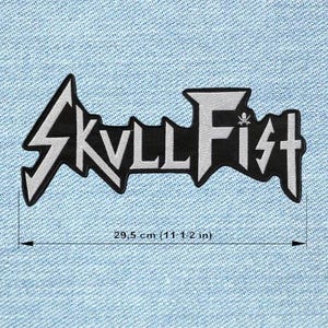 May include: A black and white Skull Fist patch, measuring 29.5 cm in length. The patch features the band's logo in a stylized font with a skull and crossbones symbol. The patch is set against a light blue denim background.