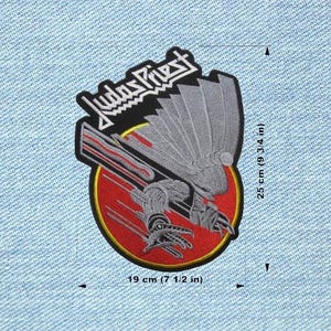 May include: An embroidered patch with the band name "Judas Priest" in white lettering. The patch features a mechanical bird design in black, grey, and red. The patch is 19 cm wide and 25 cm tall.