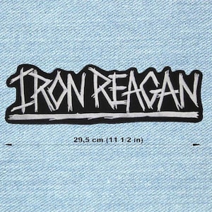 Può includere: Toppa ricamata in bianco e nero con la scritta "IRON REAGAN". La toppa misura circa 29,5 cm di lunghezza e presenta un carattere irregolare. La toppa è su uno sfondo di denim blu chiaro.