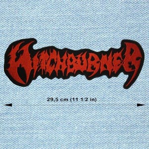 May include: A red and black embroidered patch featuring the word "WAKEBURIAL" in a stylized font. The patch measures 29.5 cm in length. The patch is on a light blue denim background.