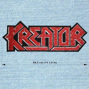 Op de afbeelding: Een rood en zwart embleem met het woord "KREATOR" in een vetgedrukte, gestileerde lettertype. Het embleem is ongeveer 29,5 cm lang en is geplaatst tegen een lichtblauwe denim achtergrond. De tekst heeft een verweerde, getextureerde uitstraling.
