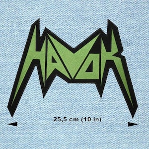 Peut inclure: Écusson brodé vert et noir avec le mot "HAVOK" dans une police stylisée. La largeur de l'écusson est de 25,5 cm et il est posé sur un fond en denim bleu clair.