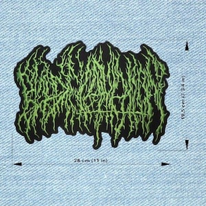 Puede incluir: Parche negro con texto verde estilizado. El parche mide 28 cm de ancho y 19,5 cm de alto. El texto tiene una apariencia irregular y orgánica. El parche está sobre un fondo de mezclilla azul claro.