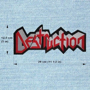 Puede incluir: Un parche rectangular con la palabra "Destruction" en rojo, gris y negro. El parche mide 29 cm de largo y 12,5 cm de alto. El parche está sobre un fondo de mezclilla azul claro.