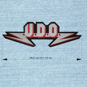 Pode incluir: Patch bordado com as letras "U.D.O." em vermelho e branco, contornadas em preto. O design inclui raios cinzentos estilizados com detalhes vermelhos, medindo 29,5 cm de largura. O patch está sobre um fundo de ganga azul claro.