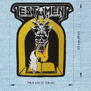 Op de afbeelding: Geborduurde patch met de bandnaam "TESTAMENT" boven een zwart-witte demonische schedel met een rode tong. De patch is 19,5 cm breed en 23 cm hoog, met een gele rand.