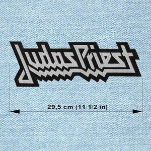 Peut inclure: Écusson brodé noir et blanc avec le nom du groupe "Judas Priest" dans une police stylisée. Le patch mesure 29,5 cm de long et est posé sur un fond en denim bleu clair.