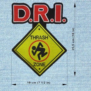 Op de afbeelding: Een patch met de tekst "D.R.I." in rode letters met een zwarte omlijning. Daaronder een gele ruit met een zwarte rand, de woorden "THRASH ZONE" en een afbeelding van een persoon. De patch is 19 cm breed en 25,5 cm hoog.