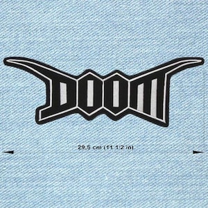 Op de afbeelding: Zwart en wit geborduurde patch met het woord "DOOM" in een gestileerd lettertype. De patch is ongeveer 29,5 cm (11 1/2 inch) breed. De patch bevindt zich op een lichtblauwe denim achtergrond.