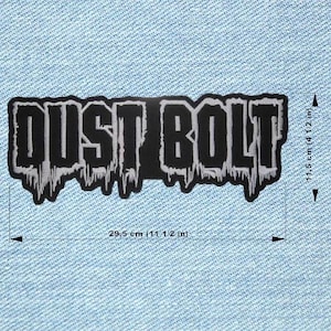 Może przedstawiać: Czarno-biała naszywka z haftem z napisem "DUST BOLT". Naszywka ma 29,5 cm długości i 11,5 cm szerokości. Tekst ma efekt kapania na dole i znajduje się na jasnoniebieskim tle z dżinsu.
