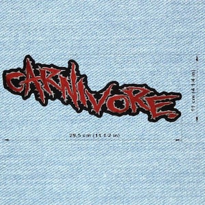 May include: A black and red embroidered patch with the word "CARNIVORE" in a stylized font. The patch measures 29.5 cm long and 11 cm high. The patch is on a light blue denim background.