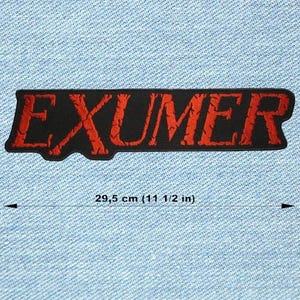 May include: Black rectangular patch with the word "EXUMER" embroidered in red, measuring 29.5 cm in length. The patch has a textured appearance and is set against a light blue denim background.