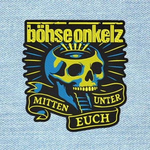Pode incluir: Um emblema bordado retangular com um gráfico de caveira em amarelo e azul, com o texto "böhse onkelz" no topo e "mitten unter euch" numa faixa na parte inferior, sobre um fundo de tecido jeans azul claro.