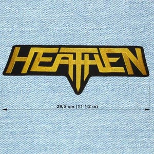 Op de afbeelding: Zwart en goud geborduurde patch met het woord "HEATHEN" in een gestileerd lettertype. De patch is 29,5 cm lang en heeft een unieke vorm met een puntige onderkant. Op een lichtblauwe denim achtergrond.
