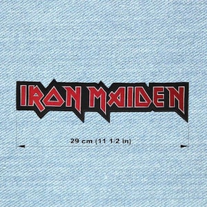 May include: A black and red Iron Maiden patch, measuring 29 cm in length. The band's name is displayed in a stylized font with a jagged border. The patch is set against a light blue denim background.