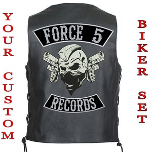 Op de afbeelding: Zwart leren bikerjack met een schedel en gekruiste beenderen ontwerp en de tekst "Force 5 Records".