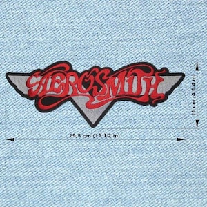 Puede incluir: Parche con el logotipo de Aerosmith, que mide 29,5 cm de ancho y 11 cm de alto. El parche presenta el nombre de la banda en letras rojas con un contorno negro, sobre un fondo gris en forma de ala. El parche está sobre un fondo de mezclilla azul claro.