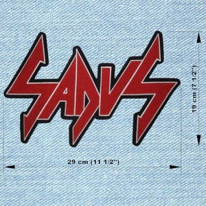 Peut inclure: Un écusson rouge et blanc avec le mot "SADVS" dans une police stylisée, souligné de noir. L'écusson mesure 29 cm de large et 19 cm de haut. L'écusson est sur un fond en denim bleu clair.