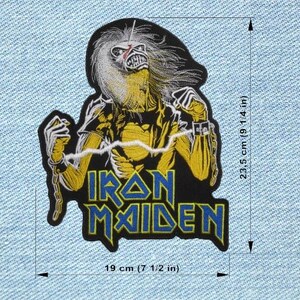 Könnte beinhalten: Gestickter Aufnäher mit dem Iron Maiden Maskottchen Eddie in einem gelb-schwarzen Design. Der Aufnäher ist 19 cm breit und 23,5 cm hoch. Der Bandname "IRON MAIDEN" ist in blauen Buchstaben mit gelber Umrandung dargestellt.