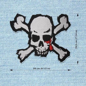 Peut inclure: Écusson tête de mort et os croisés au design vieilli. Le crâne est gris avec des orbites noires et une larme rouge. Le patch mesure 24 cm de large et 19,5 cm de haut.