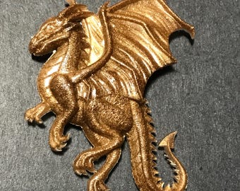 Puede incluir: Una figurita de dragón de color dorado con las alas extendidas y una superficie detallada y texturizada.