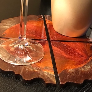 May include: Set of four coasters made of resin with a copper and gold swirl design. The coasters are shaped like triangles and have a scalloped edge.