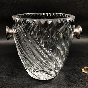 May include: A clear crystal ice bucket with a swirling pattern and silver handles.