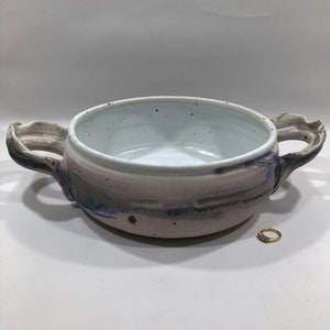 May include: A white ceramic serving bowl with two handles. The bowl has a pink, purple, and blue glaze with a speckled finish.