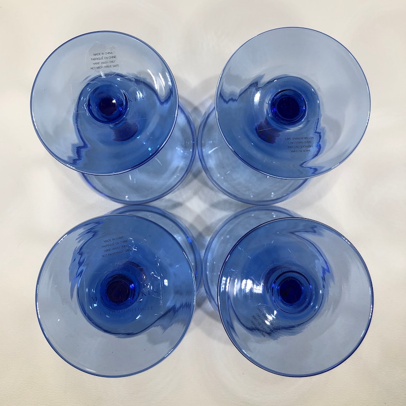 May include: Four blue glass cups with a rounded base and a flared top. The cups are made in China and are microwave and dishwasher safe.