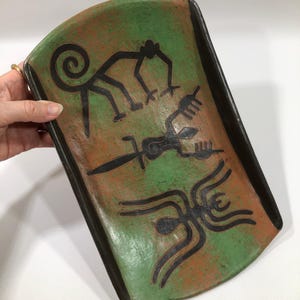 May include: A rectangular ceramic tray with rounded corners, featuring a green and terracotta-colored surface. The tray is decorated with three distinct black line-art illustrations depicting a monkey, a lizard-like creature, and a spider.