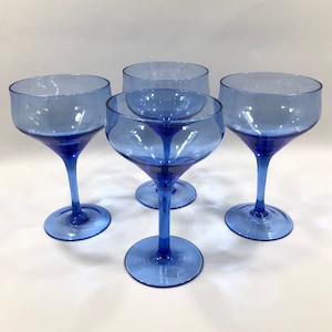 May include: Set of four cobalt blue glass stemmed cocktail glasses. The glasses have a wide bowl and a thin stem.