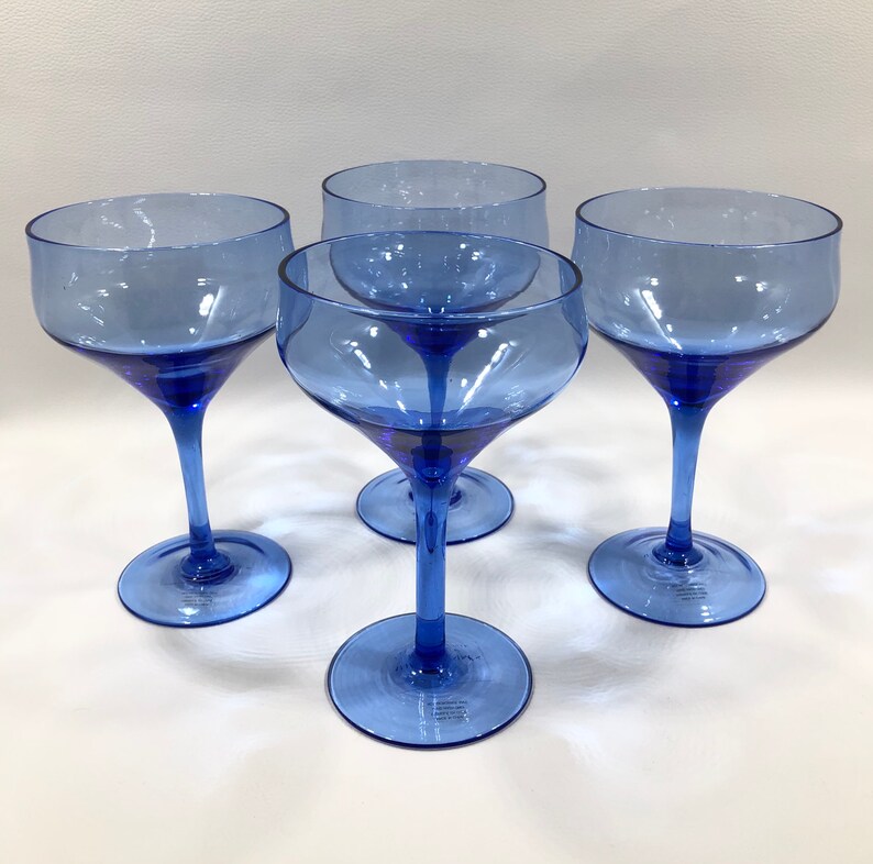 May include: Set of four cobalt blue glass stemmed cocktail glasses. The glasses have a wide bowl and a thin stem.