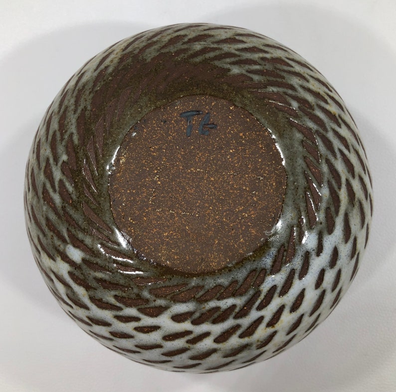 以下が含まれることがあります： 白釉薬がかけられた茶色の陶器のボウルで、織り模様が施されています。ボウルは茶色の内側で、底には「T」の文字が刻印されています。