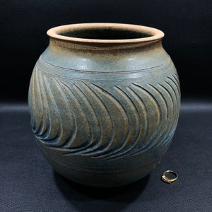 May include: A blue and brown ceramic vase with a wavy, carved design. The vase is round and has a wide opening.